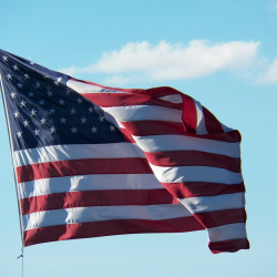US flag blowing against blue sky